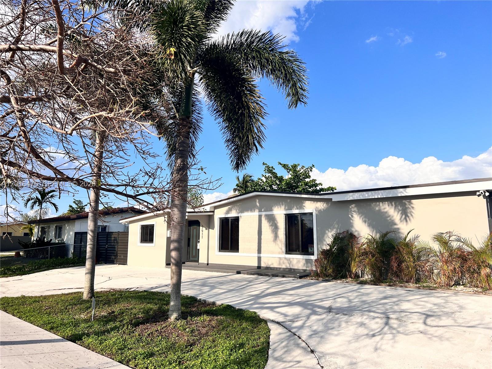 A single-story house with a concrete driveway and palm trees under a blue sky — 17911 NW 82nd Ave, Hialeah FL 33015, HIALEAH, FL