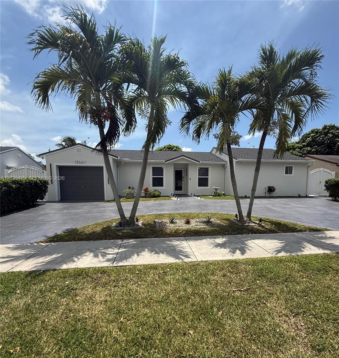 A single-story house features a gray garage, a paved driveway, and two prominent palm trees — 19331 NW 57th Ct, Miami FL 33015, MIAMI, FL