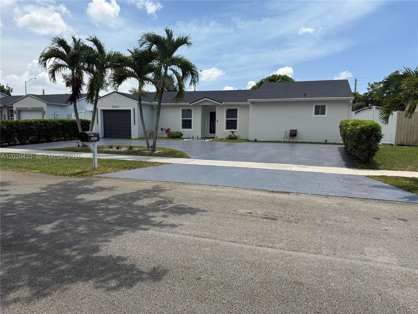 A single-story house with a gray driveway, two palm trees, and a dark garage door — 19331 NW 57th Ct, Miami FL 33015, MIAMI, FL