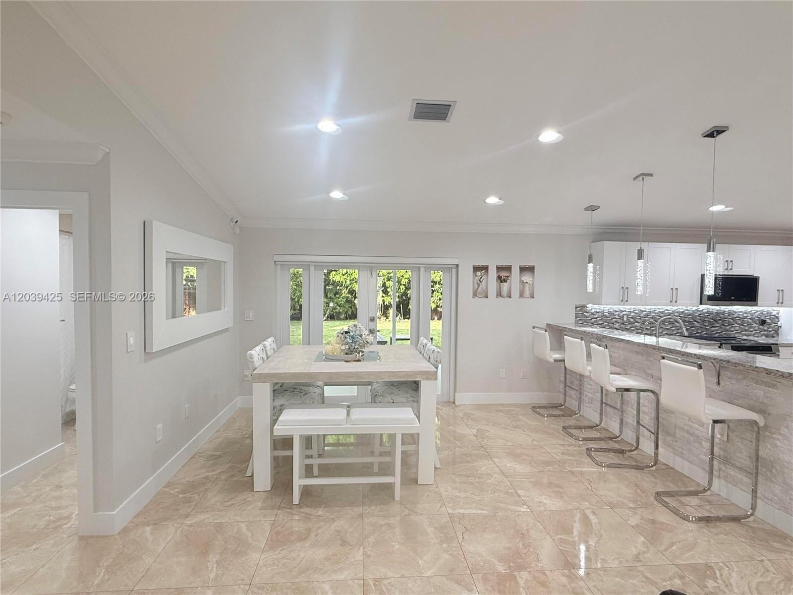 A dining area and kitchen feature tile floors, white cabinetry, and a breakfast bar — 19331 NW 57th Ct, Miami FL 33015, MIAMI, FL