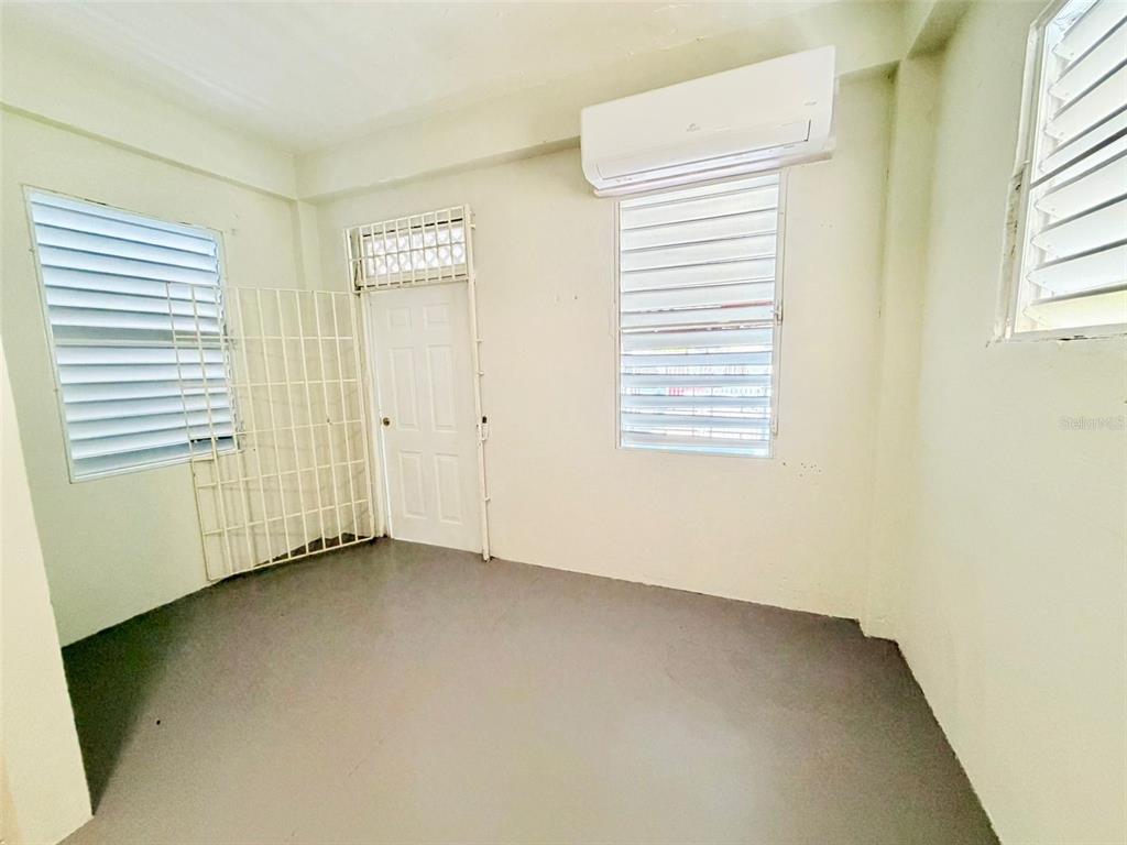 An empty room features white walls, a gray floor, louvered windows, and a wall-mounted air conditioner — 0 LIPPITT, SAN JUAN, PR