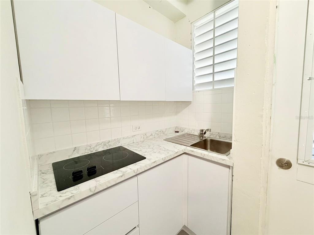 A small kitchen features white cabinets, a marble-patterned countertop, a cooktop, and a sink — 0 LIPPITT, SAN JUAN, PR