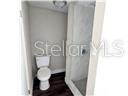 A small bathroom features a white toilet next to a walk-in shower with tiled walls — 2507 CORAL WAY, LAKELAND, FL