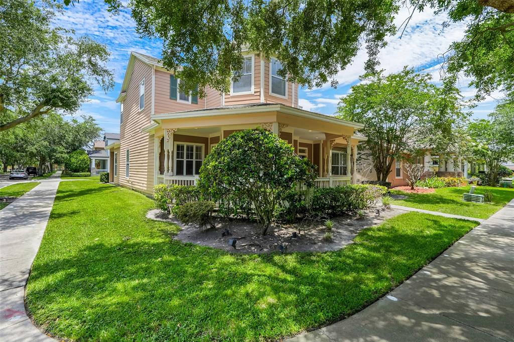A two-story house with light-colored siding and a wrap-around porch sits on a corner lot — 6601 DUNCASTER STREET, WINDERMERE, FL