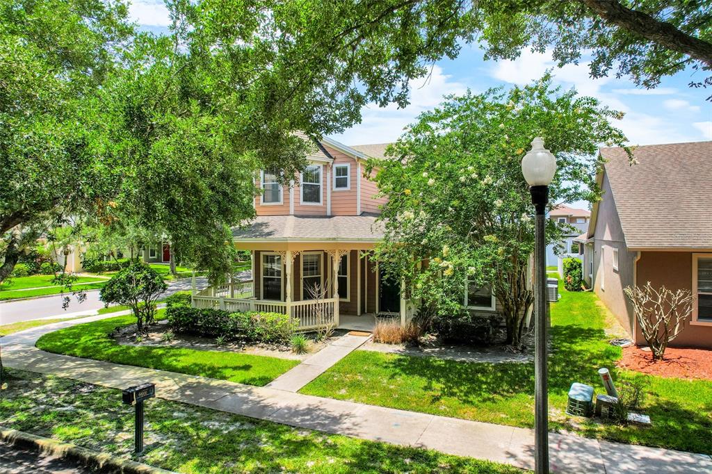 A two-story house with a wrap-around porch and light-colored siding sits behind mature trees — 6601 DUNCASTER STREET, WINDERMERE, FL