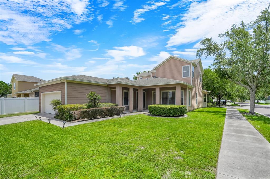 A two-story house with tan siding, a garage, and a front porch faces a lawn — 6601 DUNCASTER STREET, WINDERMERE, FL