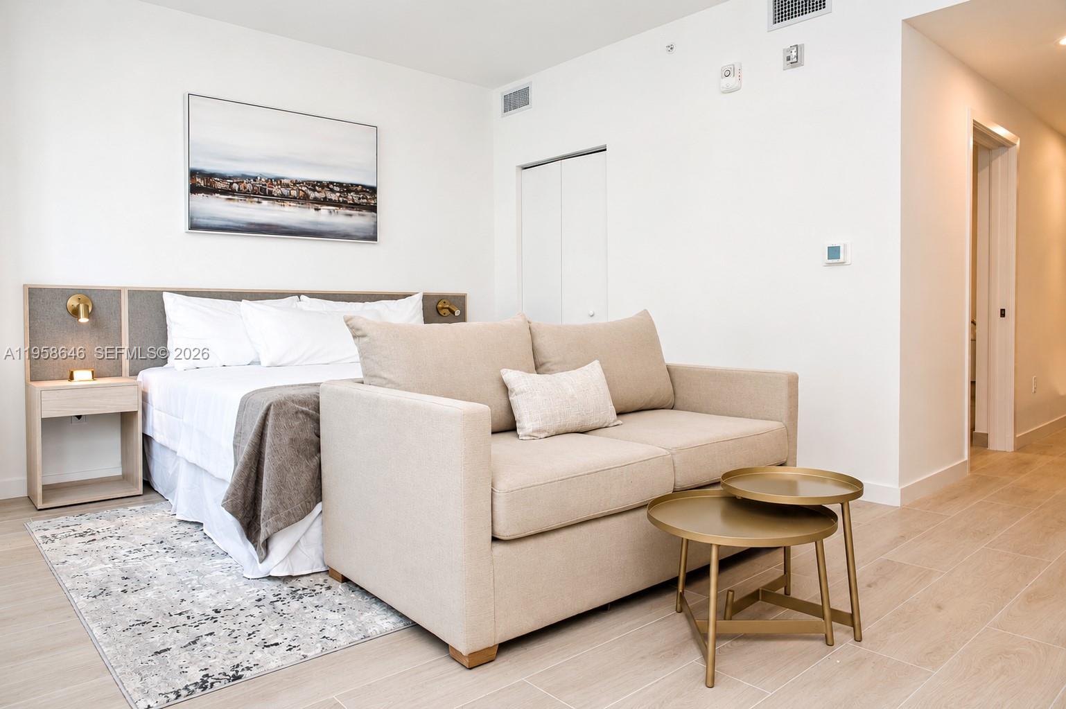 A bedroom features a bed, a beige sofa, and a small nested table set — 225 N Miami Ave # 2508, Miami FL 33128, MIAMI, FL