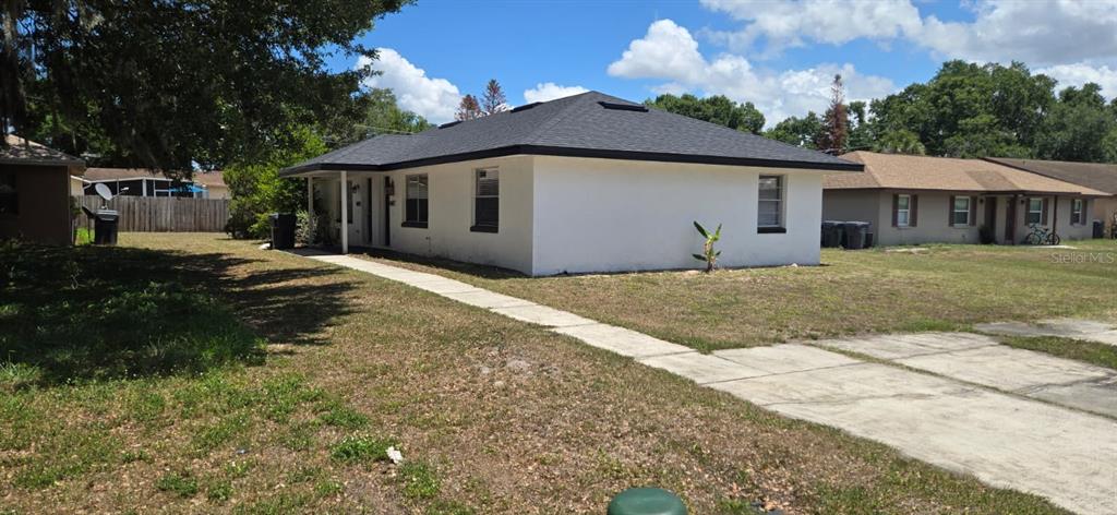 A white, single-story house with a dark roof and a concrete walkway in the yard — 5657 STRUTHERS COURT, WINTER HAVEN, FL