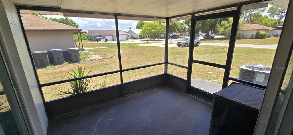 A screened-in porch with a concrete floor overlooks a grassy yard and neighborhood street — 5657 STRUTHERS COURT, WINTER HAVEN, FL
