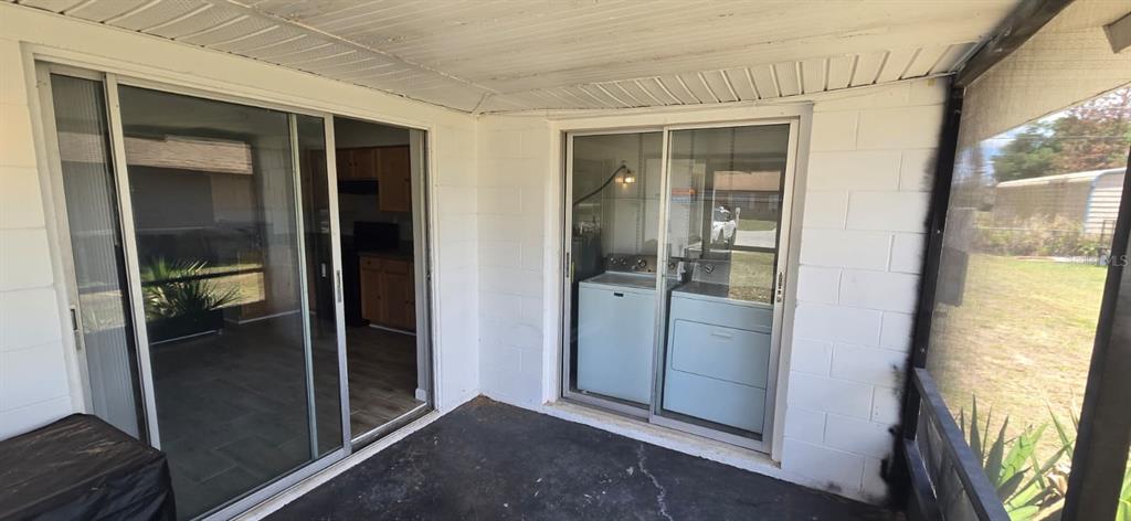 A covered patio features two sliding glass doors, one opening to a kitchen and another to laundry — 5657 STRUTHERS COURT, WINTER HAVEN, FL