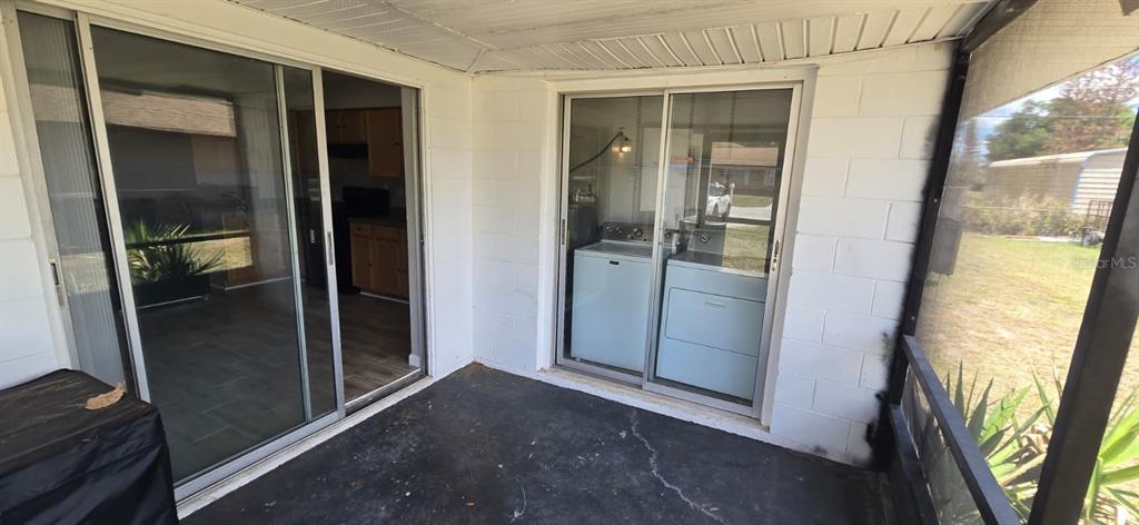 A covered patio features two sliding glass doors, one opening to a kitchen and another to laundry — 5657 STRUTHERS COURT, WINTER HAVEN, FL