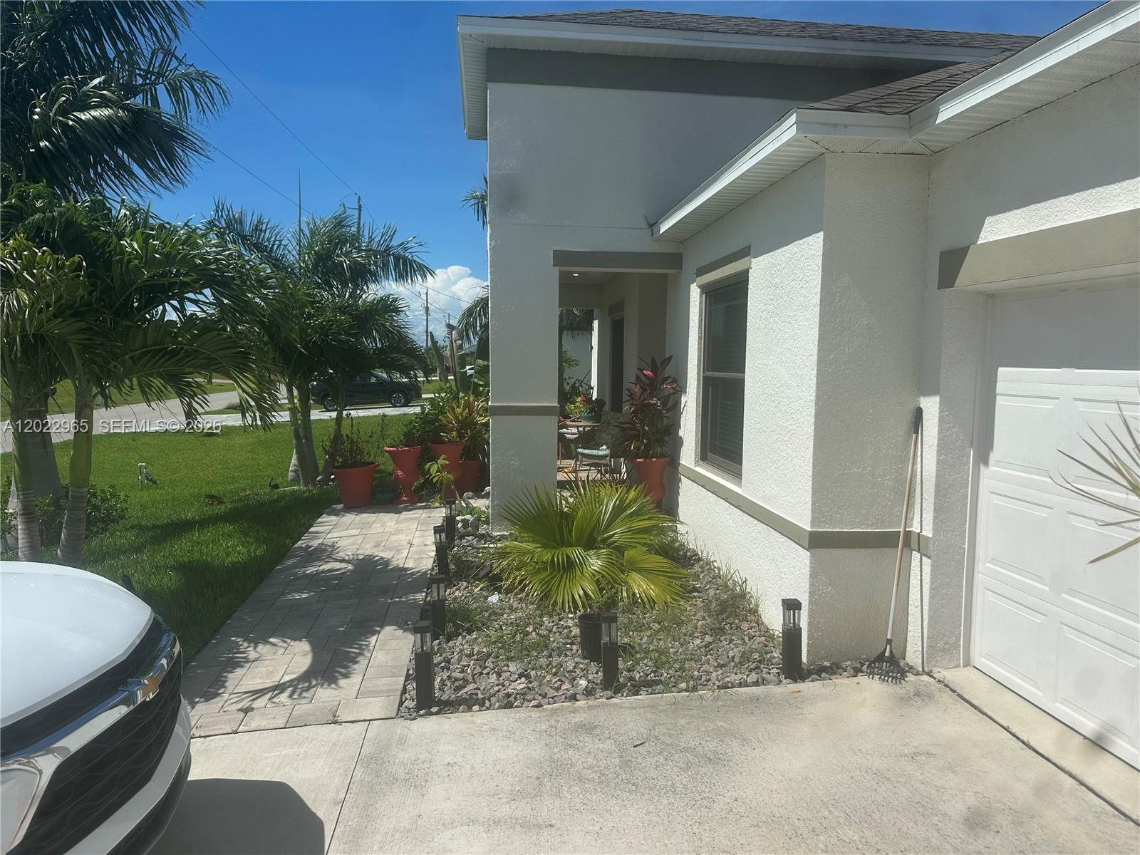 A paved walkway leads to the front entrance of a house with a white garage — 225 SW 31ST PL, Cape Coral FL 33991, CAPE CORAL, FL