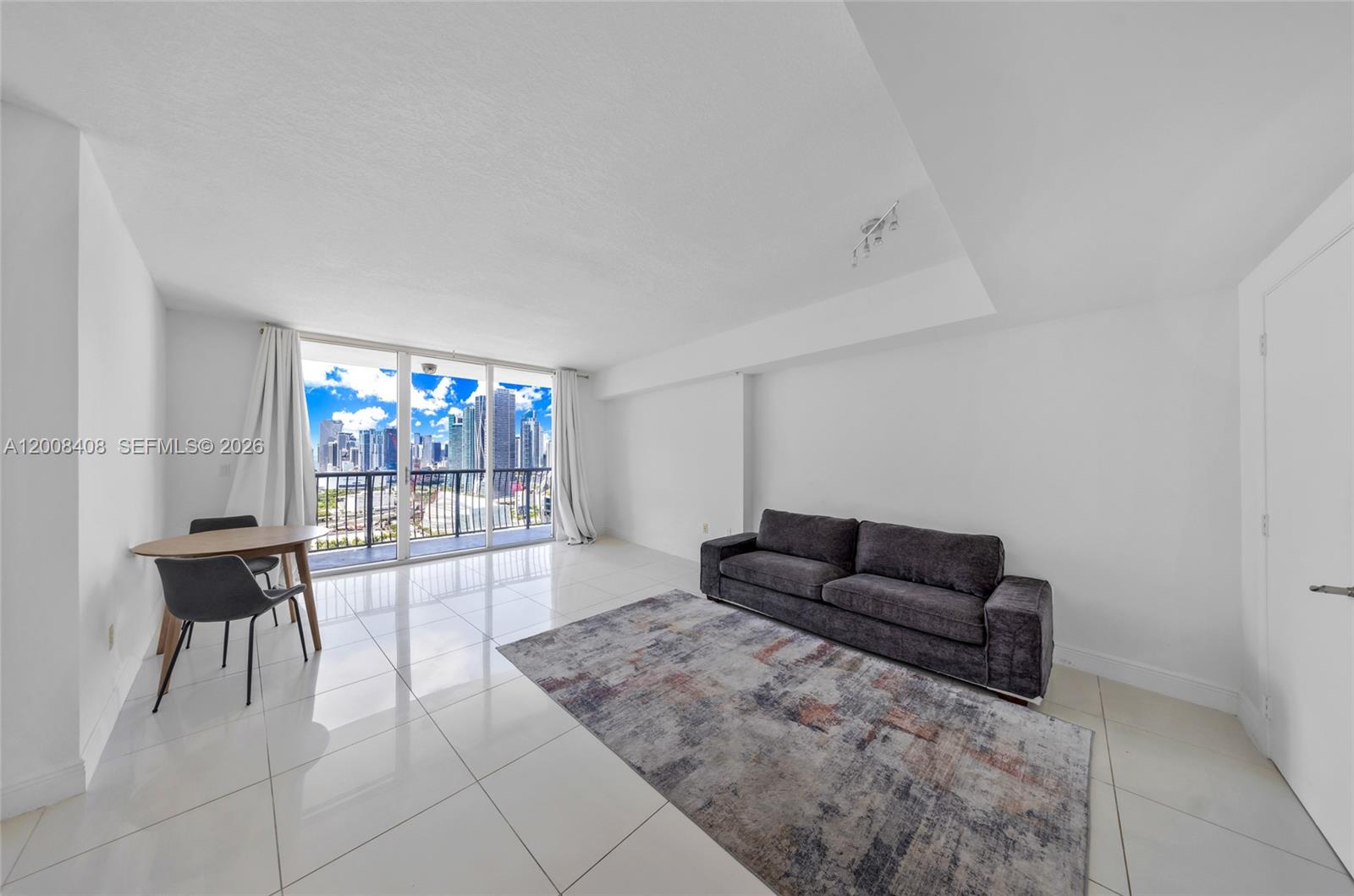A living room features white tile floors, a dark sofa on a rug, and a balcony — 1750 N Bayshore Dr # 3308, Miami FL 33132, MIAMI, FL