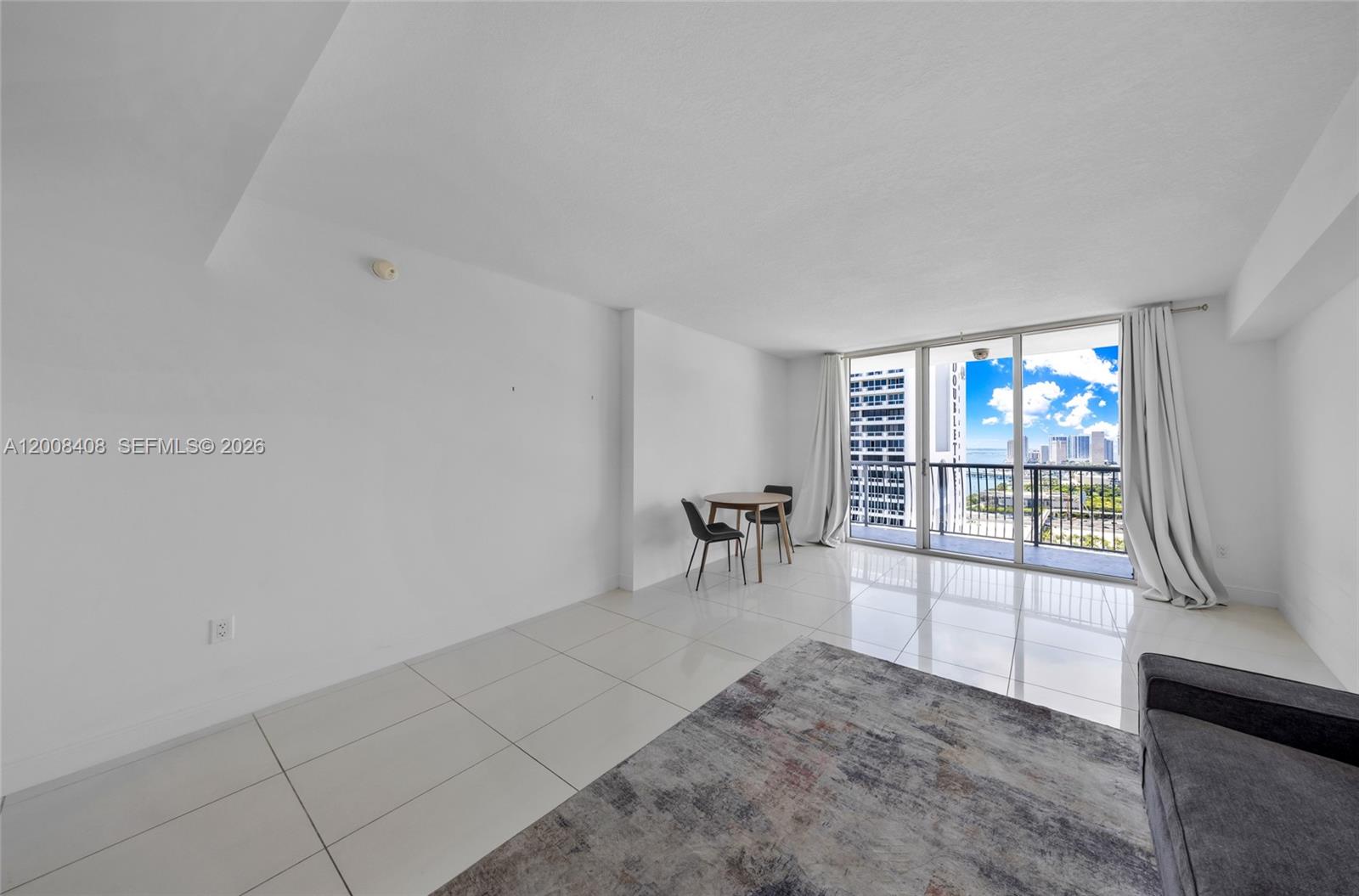 A bright living room features white tile floors, a small dining set, and balcony access — 1750 N Bayshore Dr # 3308, Miami FL 33132, MIAMI, FL