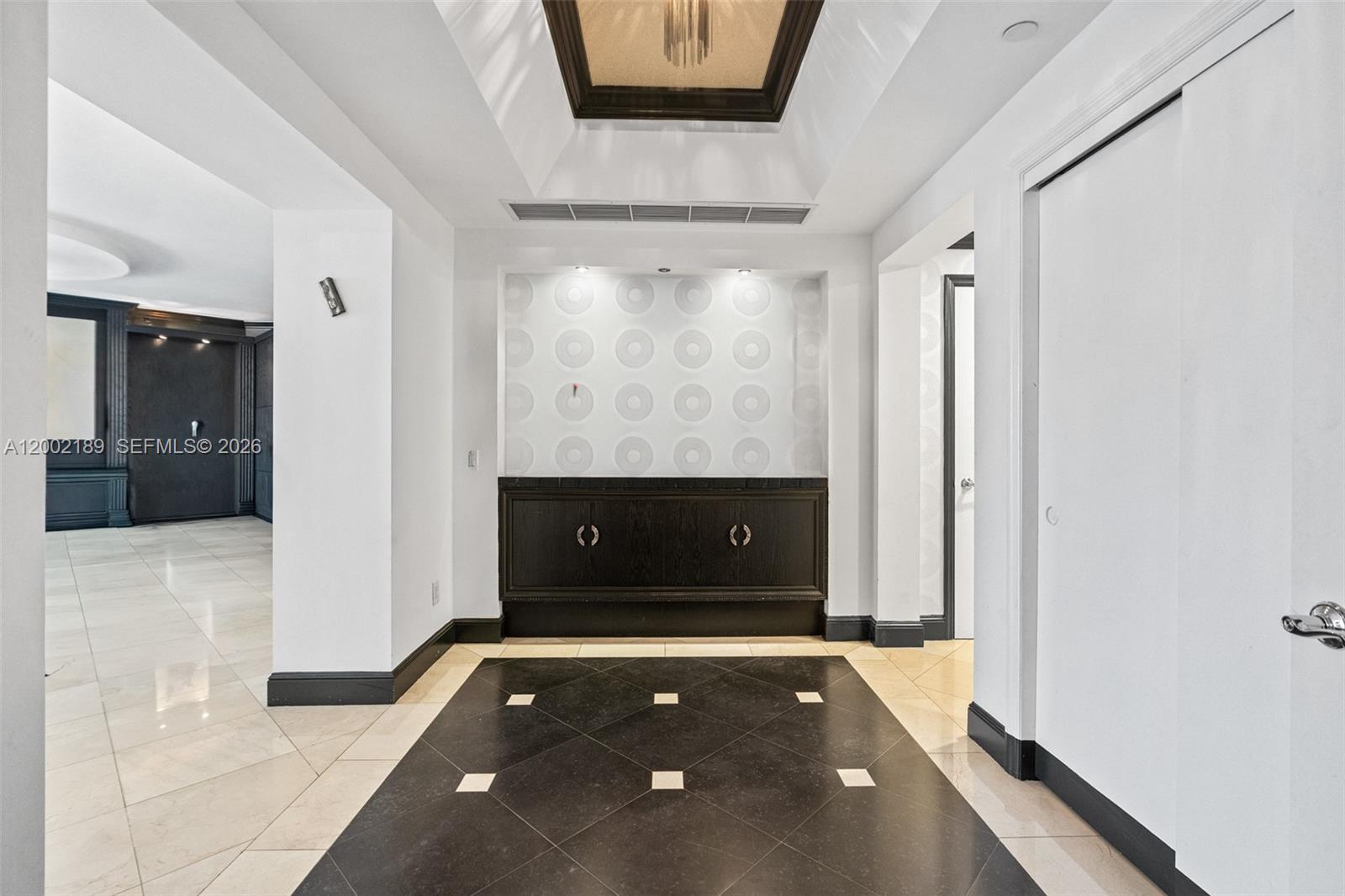 A foyer features a dark wood cabinet, patterned accent wall, and a black tiled floor — 21050 Point Pl # 403, Aventura FL 33180, AVENTURA, FL