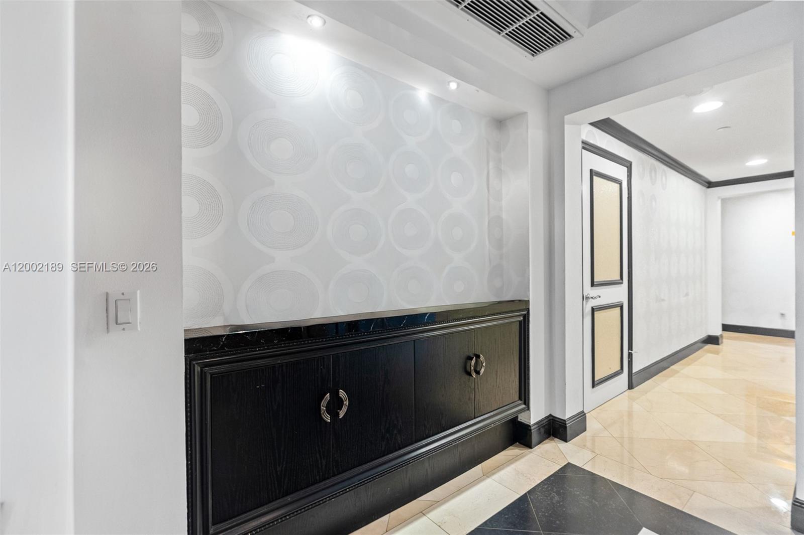 A hallway features a black built-in cabinet with a marble top and patterned wallpaper — 21050 Point Pl # 403, Aventura FL 33180, AVENTURA, FL