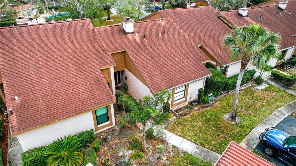 An aerial view shows the exterior of a multi-unit townhouse with a reddish-brown shingled roof — 3409 HILL MOOR DRIVE, PALM HARBOR, FL