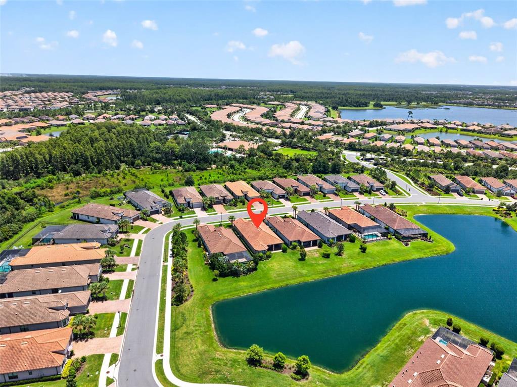 An aerial view shows a suburban neighborhood with houses surrounding a lake — 11108 CALLUNA DRIVE, ODESSA, FL