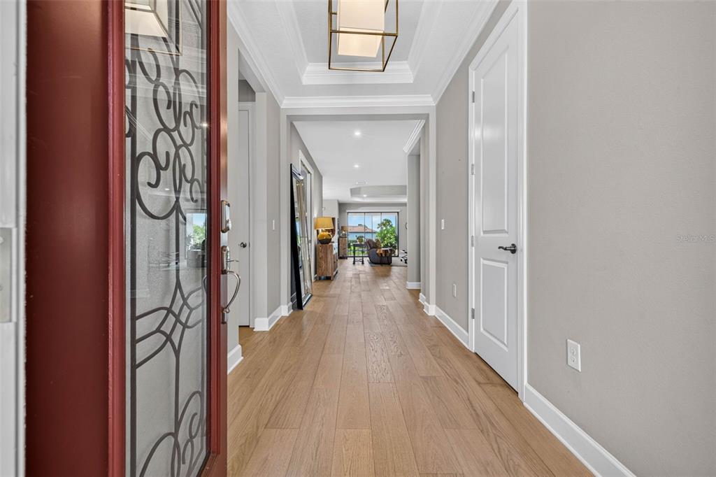 A view from an entryway into a hallway with light wood flooring and white doors — 11108 CALLUNA DRIVE, ODESSA, FL