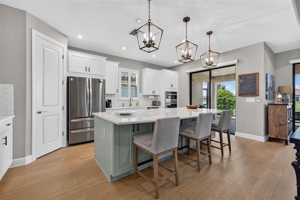 A kitchen features a light blue island with bar stools, white cabinetry, and stainless appliances — 11108 CALLUNA DRIVE, ODESSA, FL