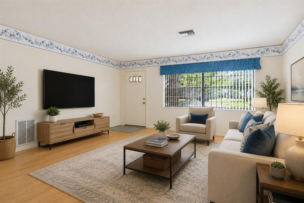 A living room features a television, a sofa, an armchair, and a coffee table — 7832 MCPHERSON DRIVE, NEW PORT RICHEY, FL