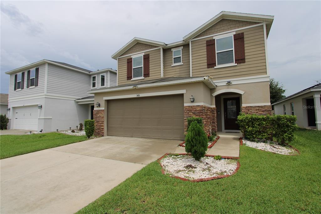 A two-story suburban house with a tan exterior, stone accents, and a two-car garage — 366 PRESERVE POINTE BOULEVARD, DAVENPORT, FL