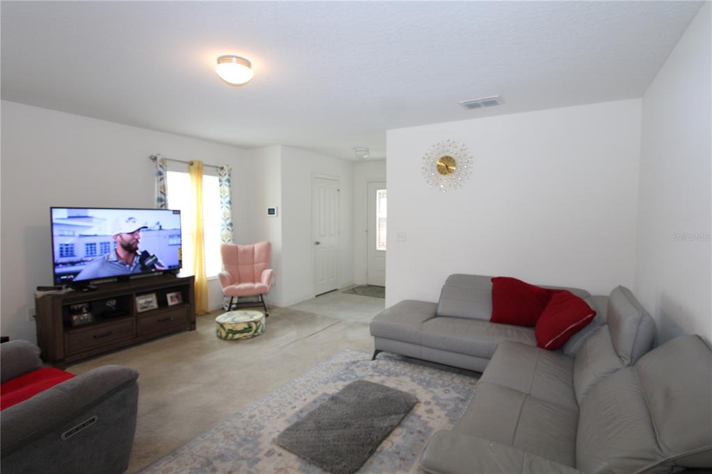 A living room features a grey sectional sofa, a television on a stand, and carpeted floors — 366 PRESERVE POINTE BOULEVARD, DAVENPORT, FL