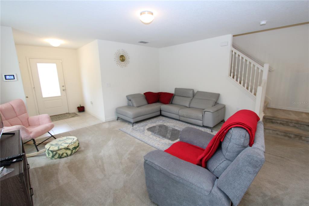 A living room features a gray sectional, a matching recliner, and a pink accent chair — 366 PRESERVE POINTE BOULEVARD, DAVENPORT, FL