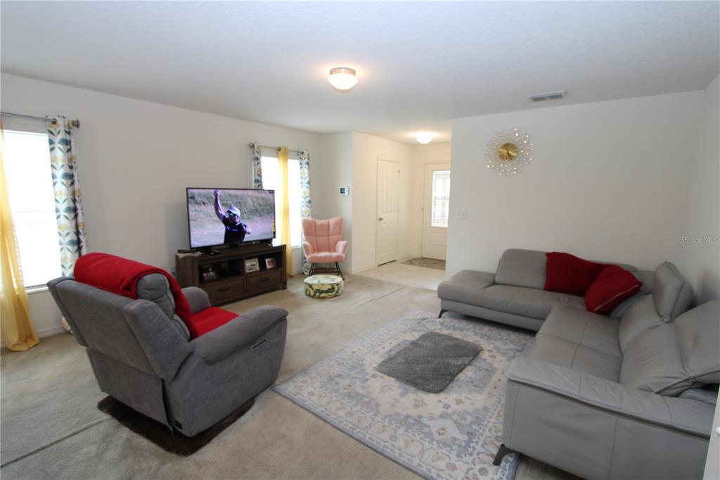 A living room features a gray sectional sofa, a recliner, and a television on a stand — 366 PRESERVE POINTE BOULEVARD, DAVENPORT, FL