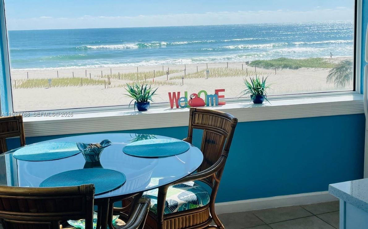 A dining area with a glass table and wicker chairs overlooks a sandy beach — 3401 NE 10th St # 12, Pompano Beach FL 33062, POMPANO BEACH, FL