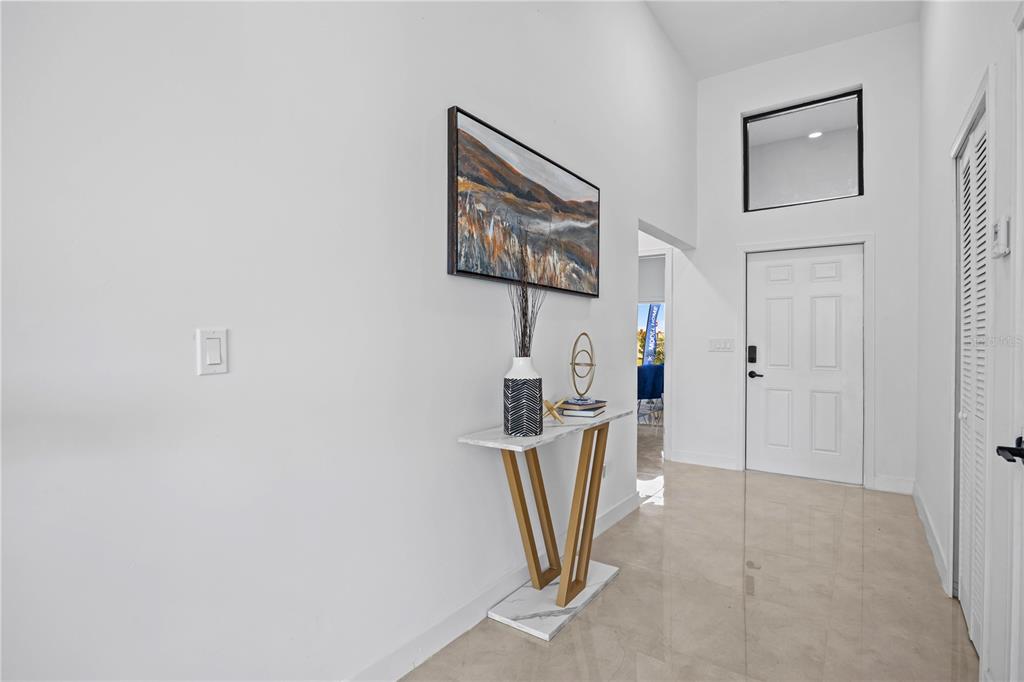 A bright entryway features a white door, a marble-topped console table, and high ceilings — 6414 QUARTET STREET, MASCOTTE, FL
