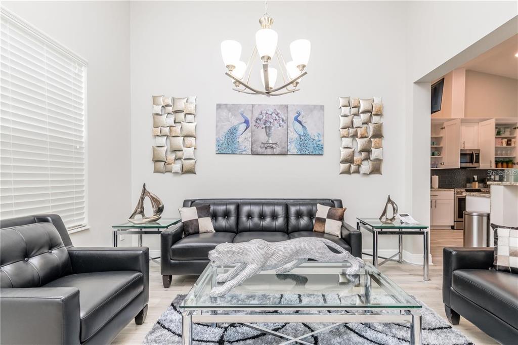 A living room features black leather furniture, a glass coffee table, and a triptych peacock painting — 5816 LITTLE RIVER DRIVE, TAMPA, FL