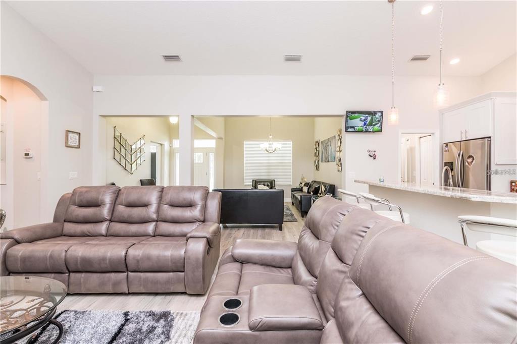 A living room features two brown leather sofas, a kitchen island, and light-colored flooring — 5816 LITTLE RIVER DRIVE, TAMPA, FL