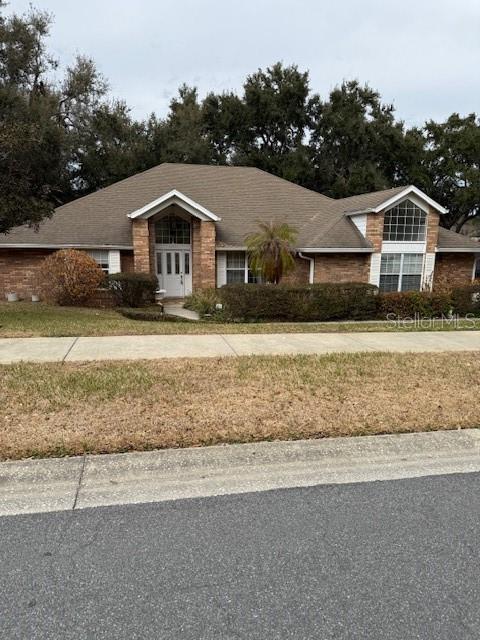 A single-story brick house with a gabled roof and a palm tree in the front yard — 14747 GREEN VALLEY BOULEVARD, CLERMONT, FL