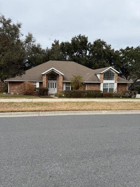 A single-story brick house with a gabled roof sits behind a lawn and street — 14747 GREEN VALLEY BOULEVARD, CLERMONT, FL