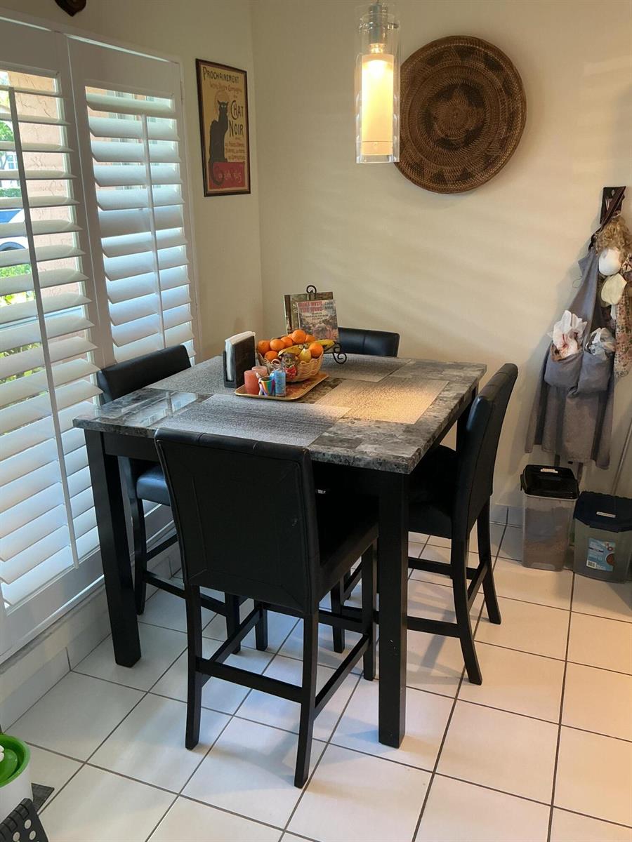 A dining area features a square marble-topped table with four black chairs on tiled flooring — 1580 NW 18th Avenue # B, Delray Beach FL 33445, DELRAY BEACH, FL