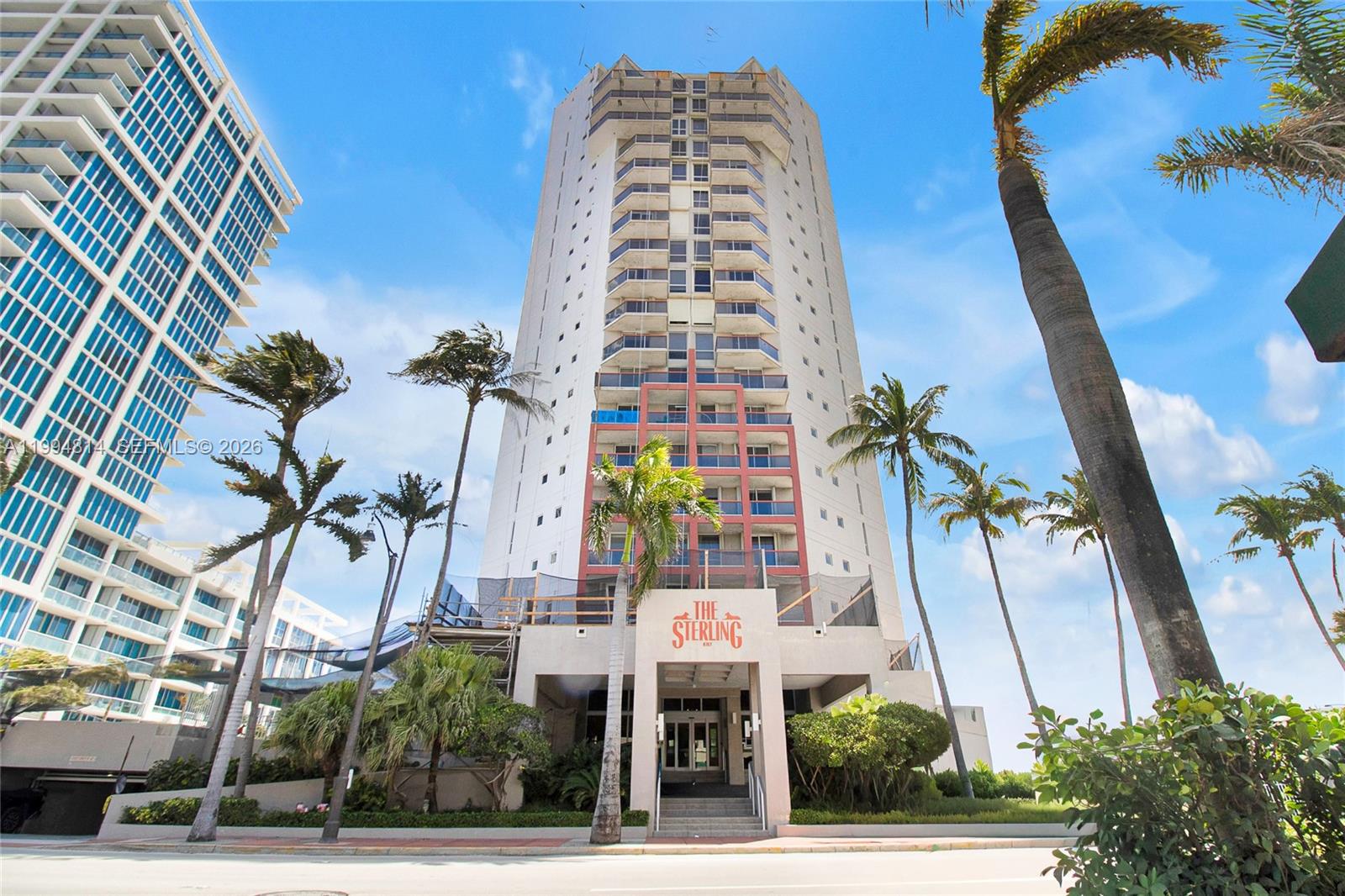 The exterior of a tall, multi-story residential building features balconies and a prominent entrance sign — 6767 Collins Ave # 504, Miami Beach FL 33141, MIAMI BEACH, FL