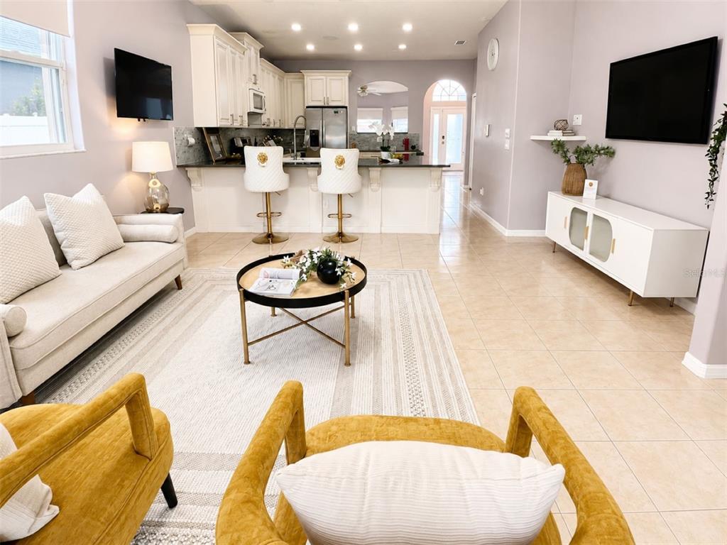 An open-concept living room features a kitchen with a breakfast bar and tile flooring — 10209 ANDOVER POINT CIRCLE, ORLANDO, FL