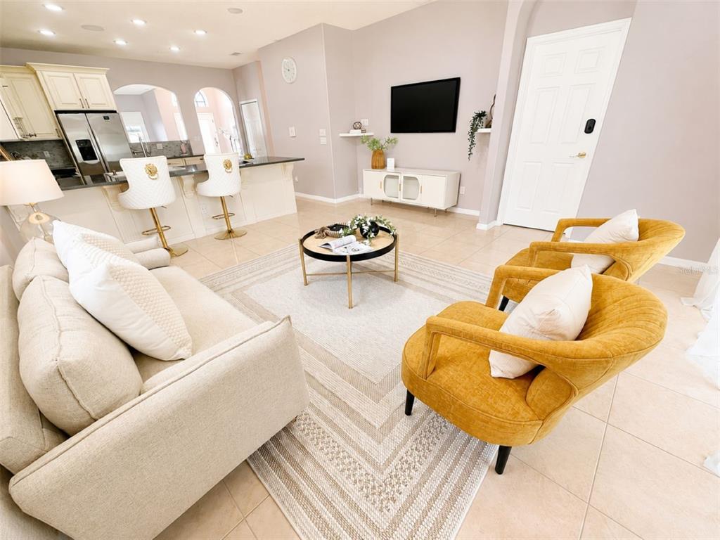 A living room features a beige sofa, two yellow armchairs, and a kitchen island — 10209 ANDOVER POINT CIRCLE, ORLANDO, FL
