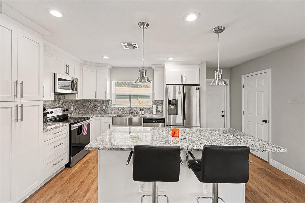 A kitchen features white cabinets, granite countertops, stainless steel appliances, and a central island — 6504 N 21ST STREET, TAMPA, FL