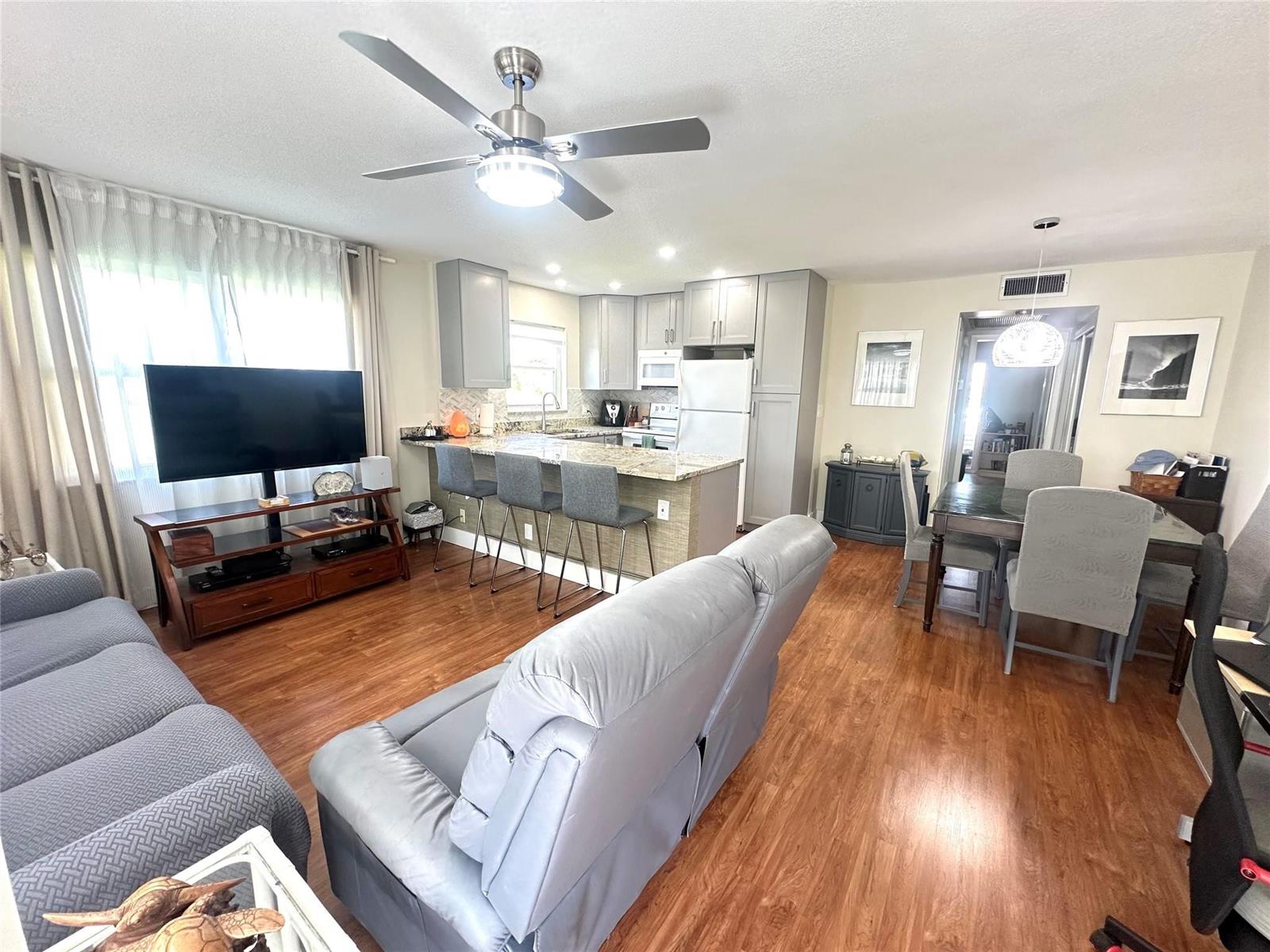 An open-concept living and dining area features wood-look flooring, gray cabinetry, and a kitchen island — 528 Tilford X # 528, Deerfield Beach FL 33442, DEERFIELD BEACH, FL