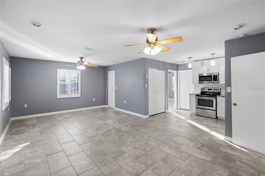 A living room with gray walls, tile flooring, two ceiling fans, and white plantation shutters — 3611 W ANDERSON AVENUE, TAMPA, FL