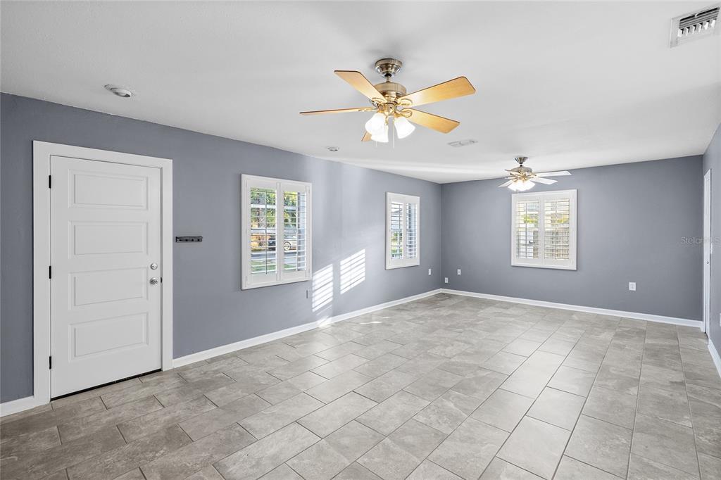 A room with gray walls, tile flooring, two ceiling fans, and white plantation shutters — 3611 W ANDERSON AVENUE, TAMPA, FL