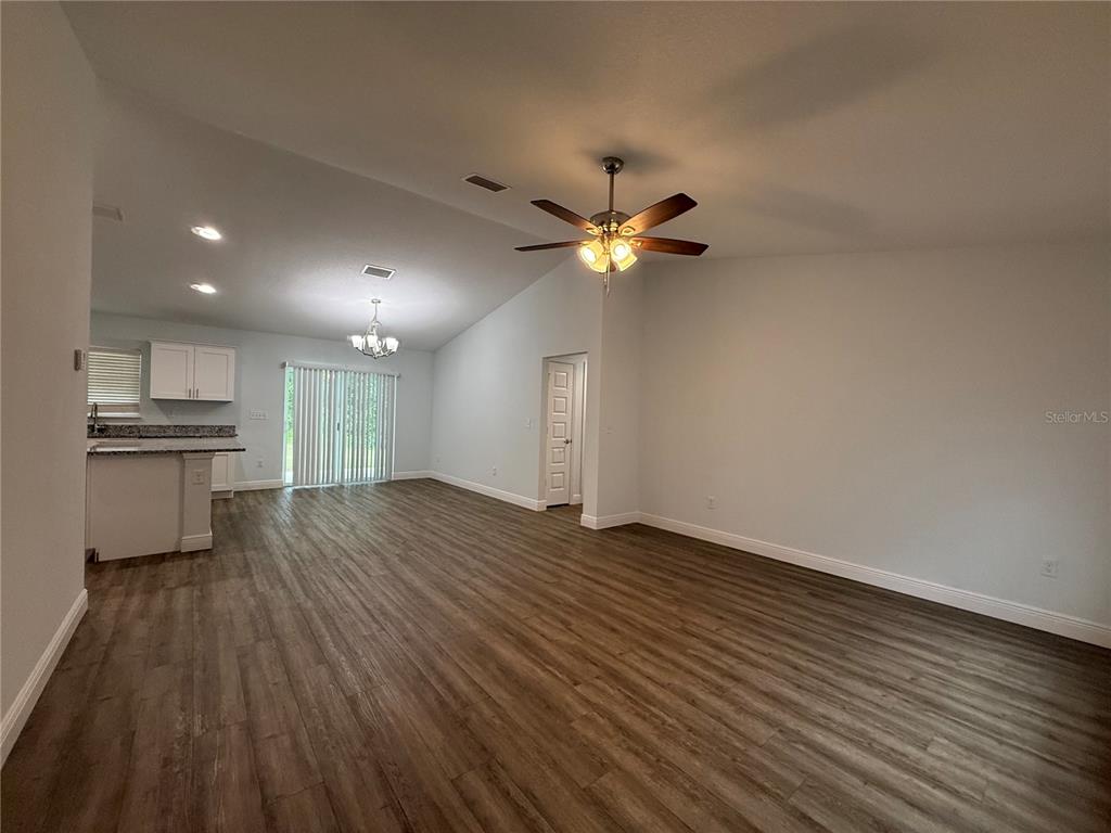 A spacious living area with wood-look flooring, a vaulted ceiling, and an open kitchen — 7752 N WALTON TERRACE, CITRUS SPRINGS, FL