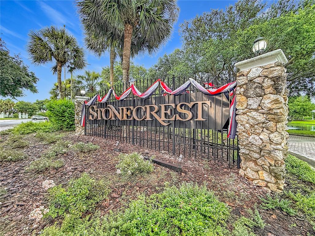 A stone-pillared entrance sign for Stonecrest features decorative red, white, and blue bunting — 11363 SE 177TH LANE, SUMMERFIELD, FL
