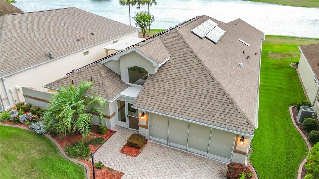 An aerial view shows a house with a shingled roof, solar panels, and a paver driveway — 11363 SE 177TH LANE, SUMMERFIELD, FL