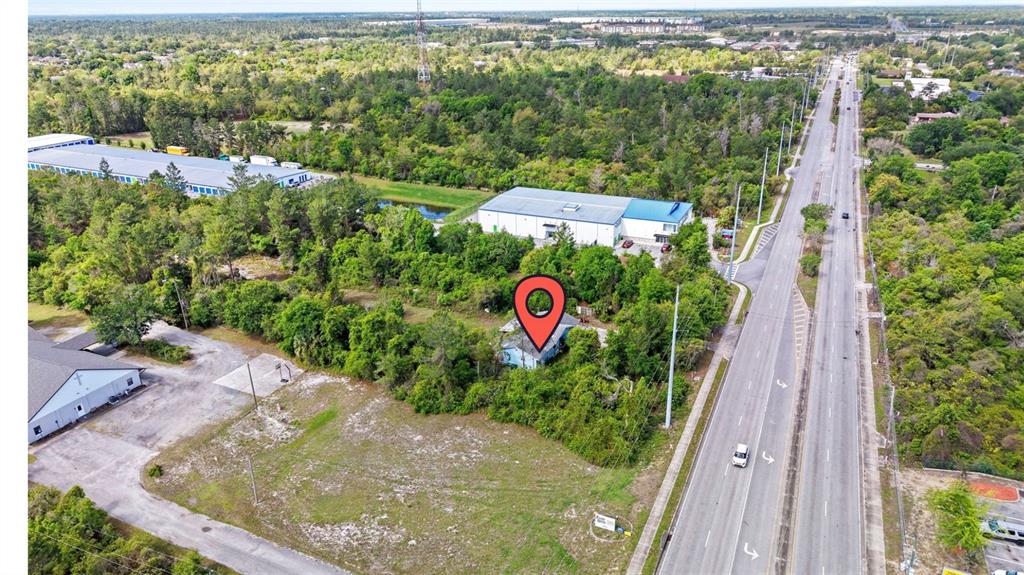 An aerial view shows a small house with a red map pin surrounded by dense vegetation — 3021 HOWLAND BOULEVARD, DELTONA, FL