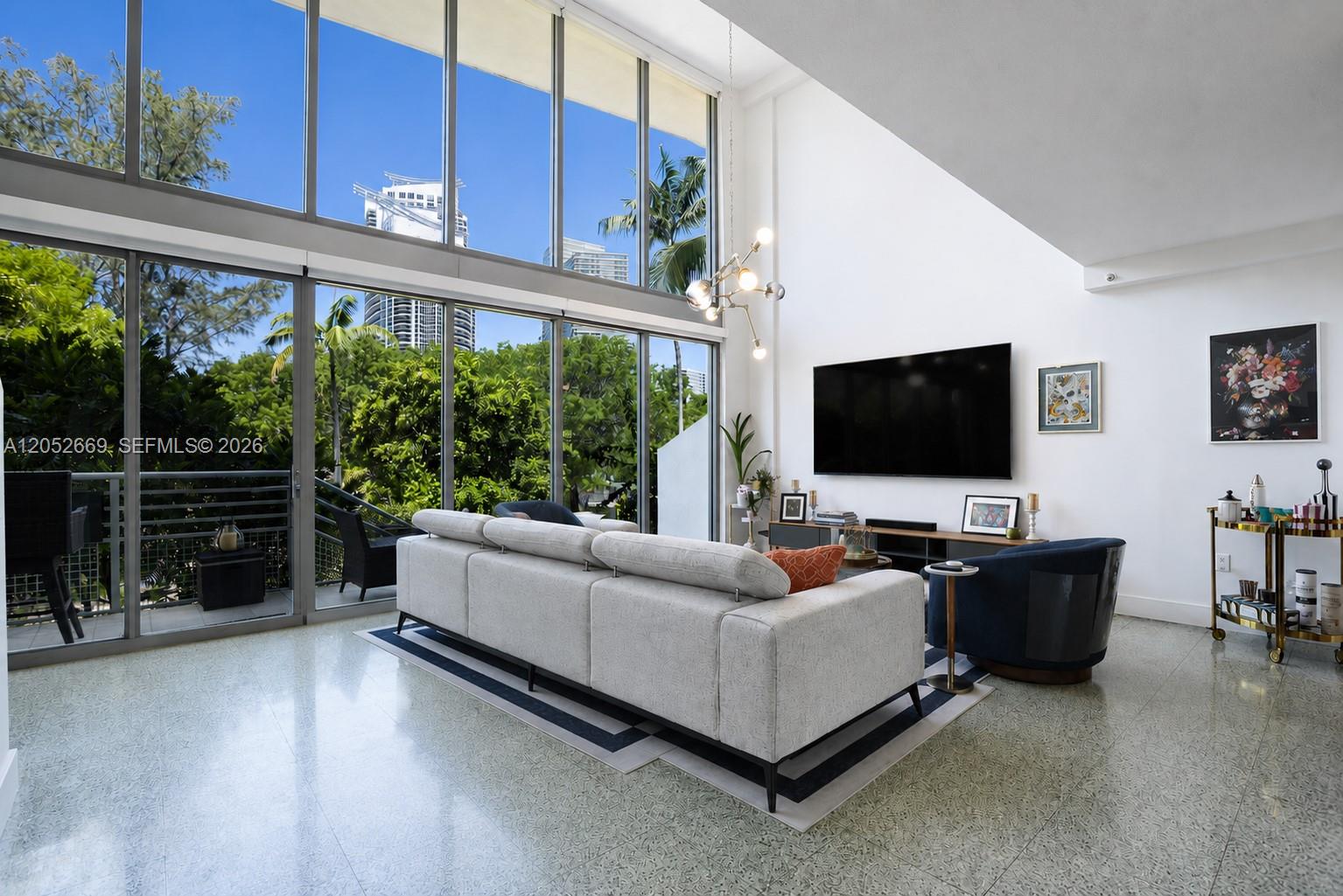A modern living room features floor-to-ceiling windows, a white sofa, and polished concrete floors — 245 Michigan Ave # 5, Miami Beach FL 33139, MIAMI BEACH, FL