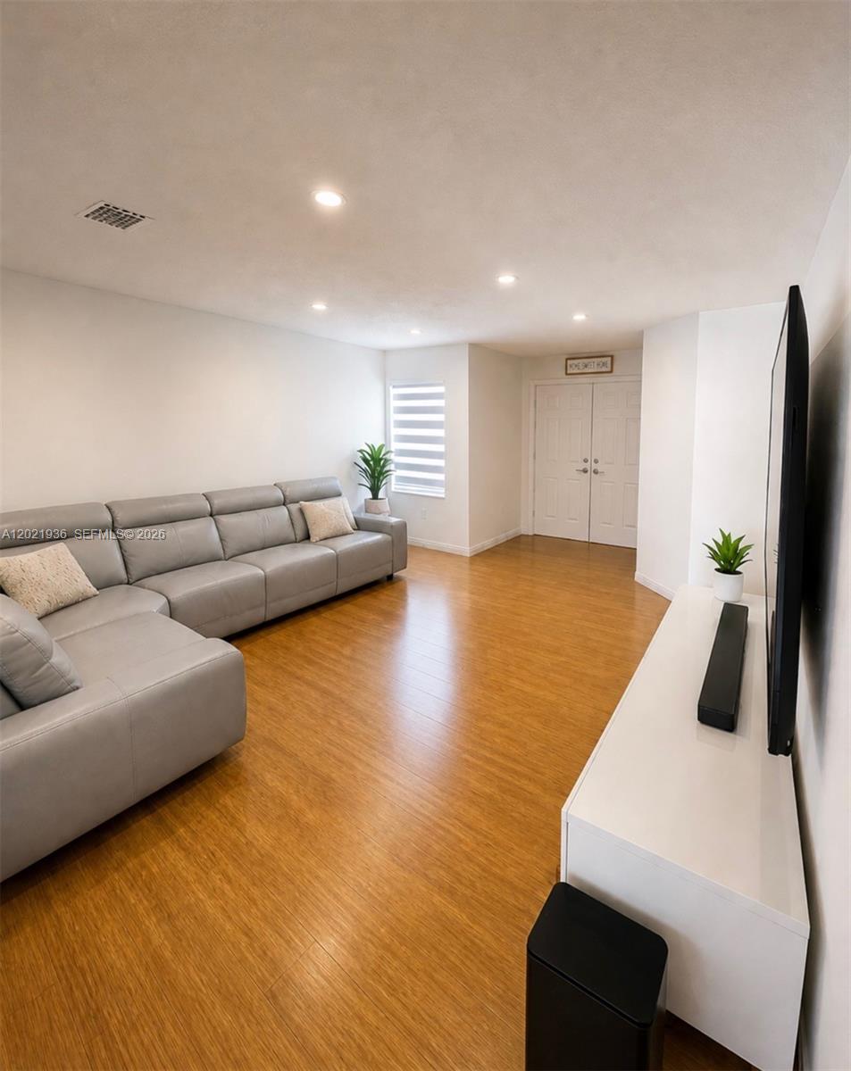 A living room features a large gray sectional sofa, light wood flooring, and a television — 16342 SW 45th Ter, Miami FL 33185, MIAMI, FL