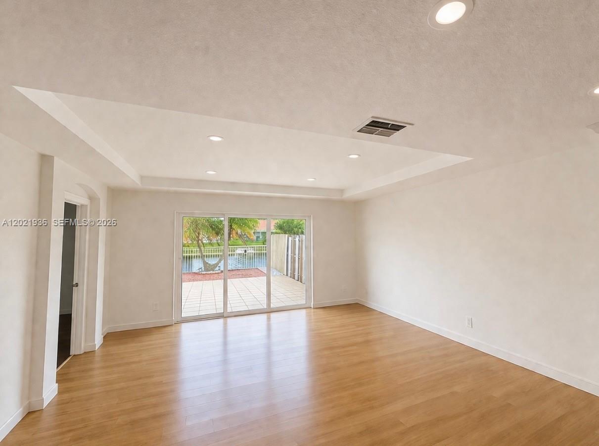 A bright living room features light wood flooring, recessed lighting, and sliding glass patio doors — 16342 SW 45th Ter, Miami FL 33185, MIAMI, FL